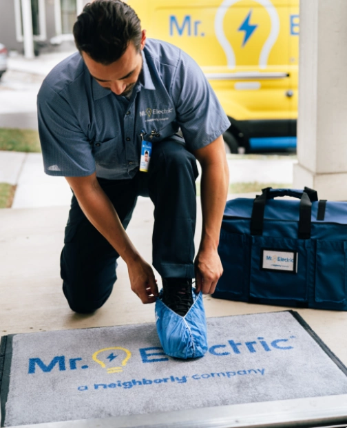 Electrician putting on shoe covers at front door.