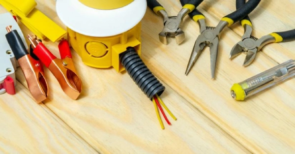 A selection of tools and parts waiting to be used by an electrician in Black Forest, CO, including pliers, clamps, and wires.