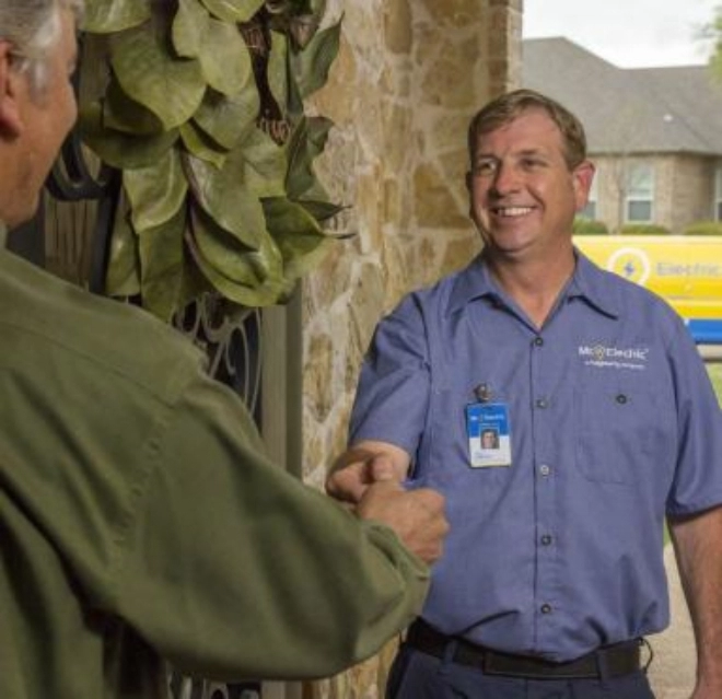 Smiling male Mr. Electric technician shaking hands with customer.