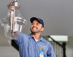 Male electrician installing ceiling light fixture.