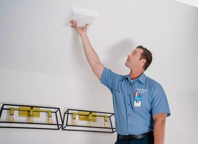 A Mr. Electric electrician installing a carbon monoxide detector