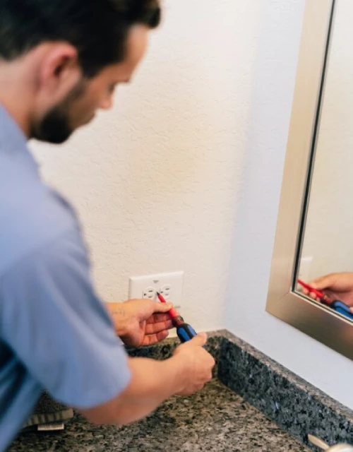 Mr. Electric electrician installing bathroom outlet.