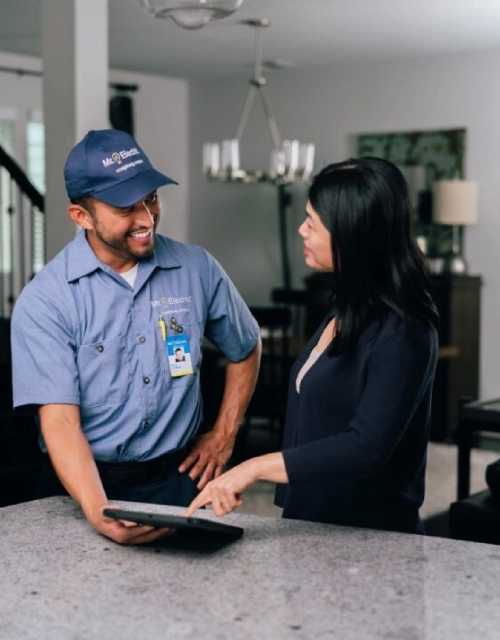 Mr. Electric technician showing tablet to customer.