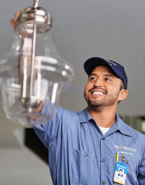 MRE tech smiling while hanging light fixture.