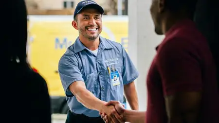 Mr. Electric technician standing at the front door, shaking hands with a man who stands next to a woman at the threshold.