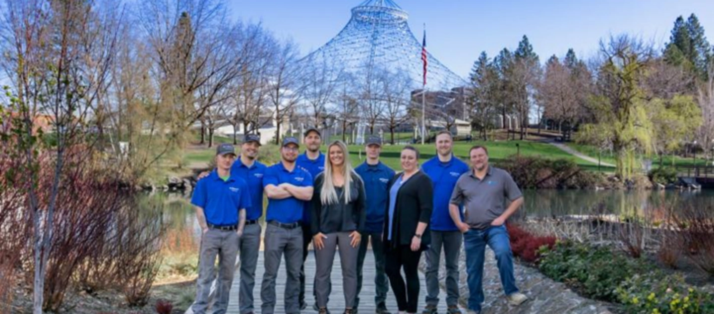 The Mr. Electric of Spokane Crew Standing Together on a Boardwalk in Front of a Landmark.