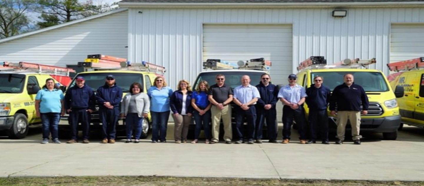 The Mr. Electric of Central Michigan Crew Standing Shoulder To Shoulder In Front Of Their Mr. Electric Vans.