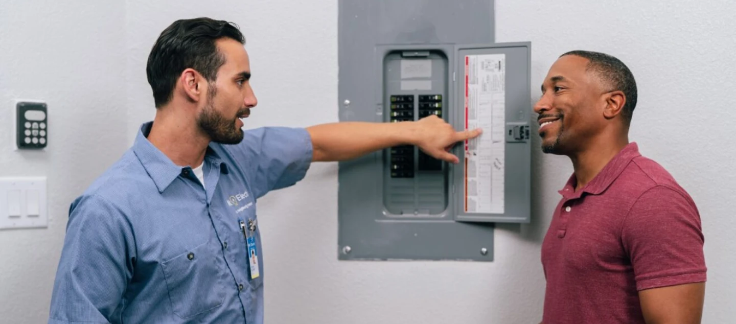 Mr. Electric electrician standing with customer showing electrical circuit breaker box.