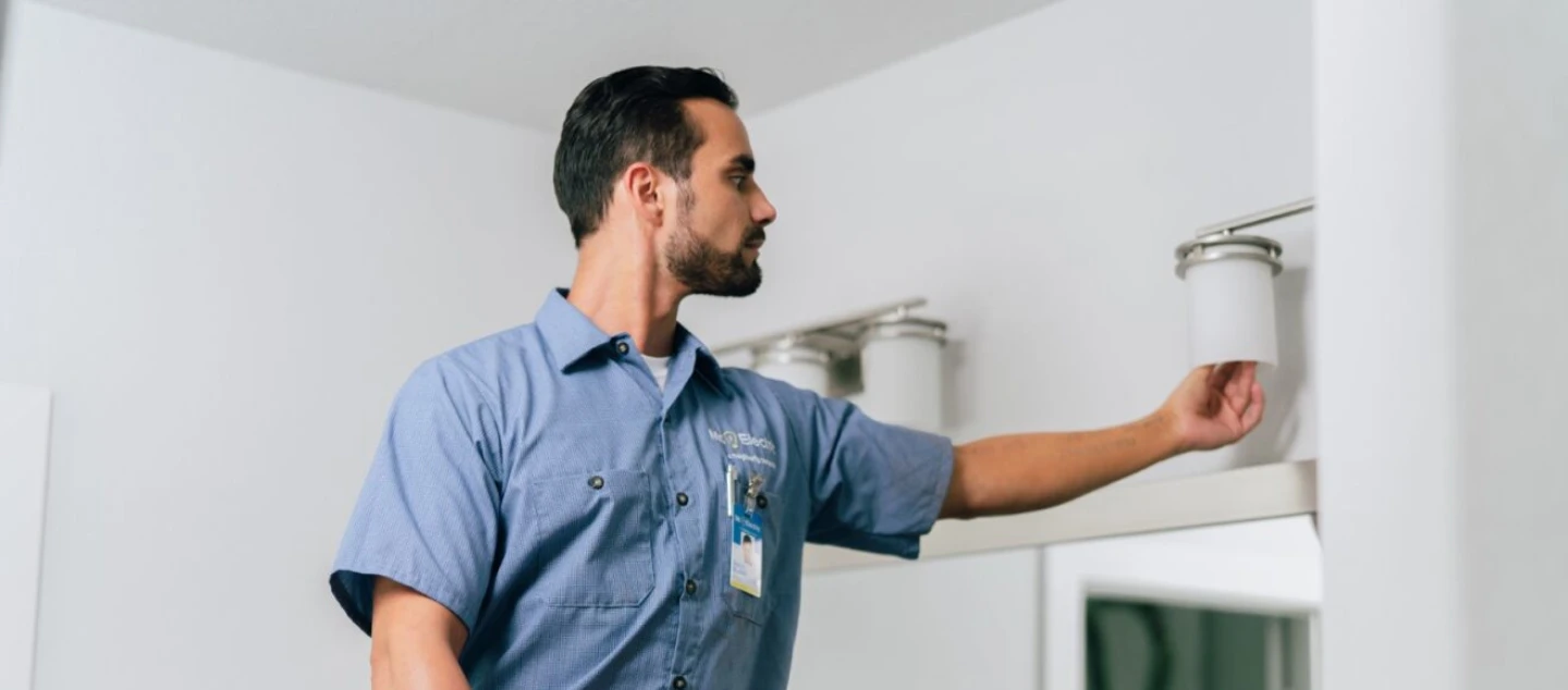 Mr. Electric technician installing bathroom light fixture.