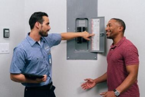 Mr. Eelctric technician showing a homeowner details about his electrical panel during an electrical service call.