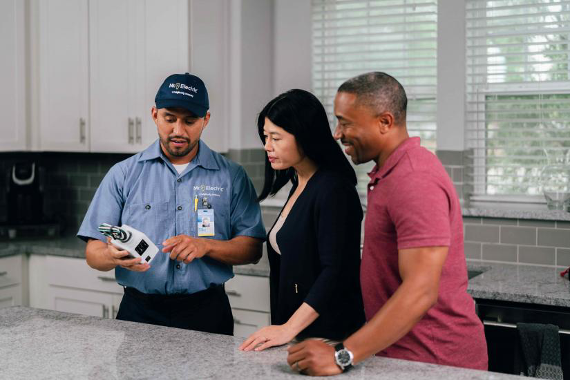 Mr. Electric electrician showing electrical panel to customers.