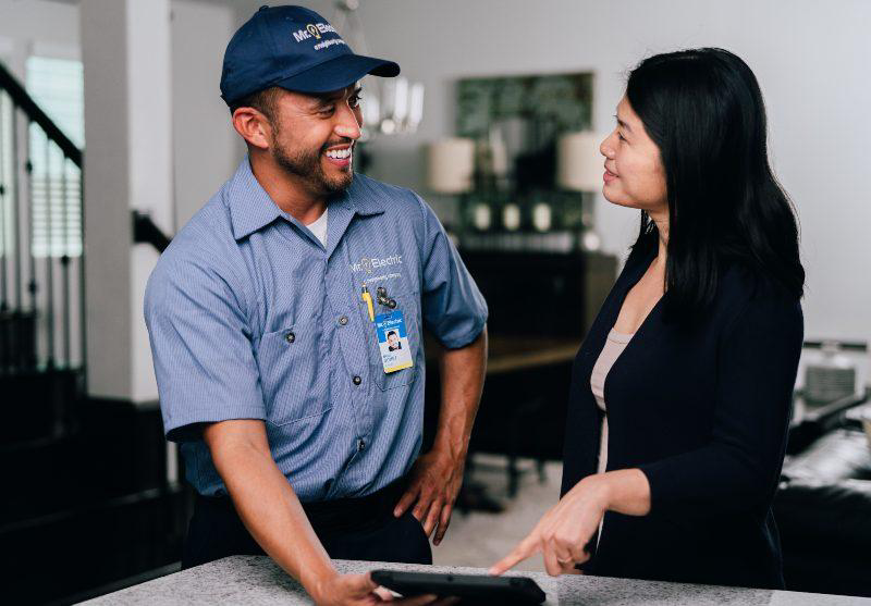 Mr. Electric service professional smiling while showing a quote for an electrical service to a woman in her home.