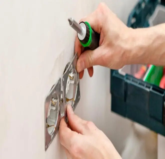 The hands of an electrician holding a screwdriver and adjusting part of an electrical outlet during an appointment for electrical installation in Colorado Springs.