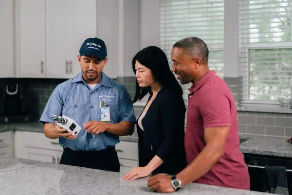 Mr. Electric technician talking to a couple in their kitchen about their electrical service project.