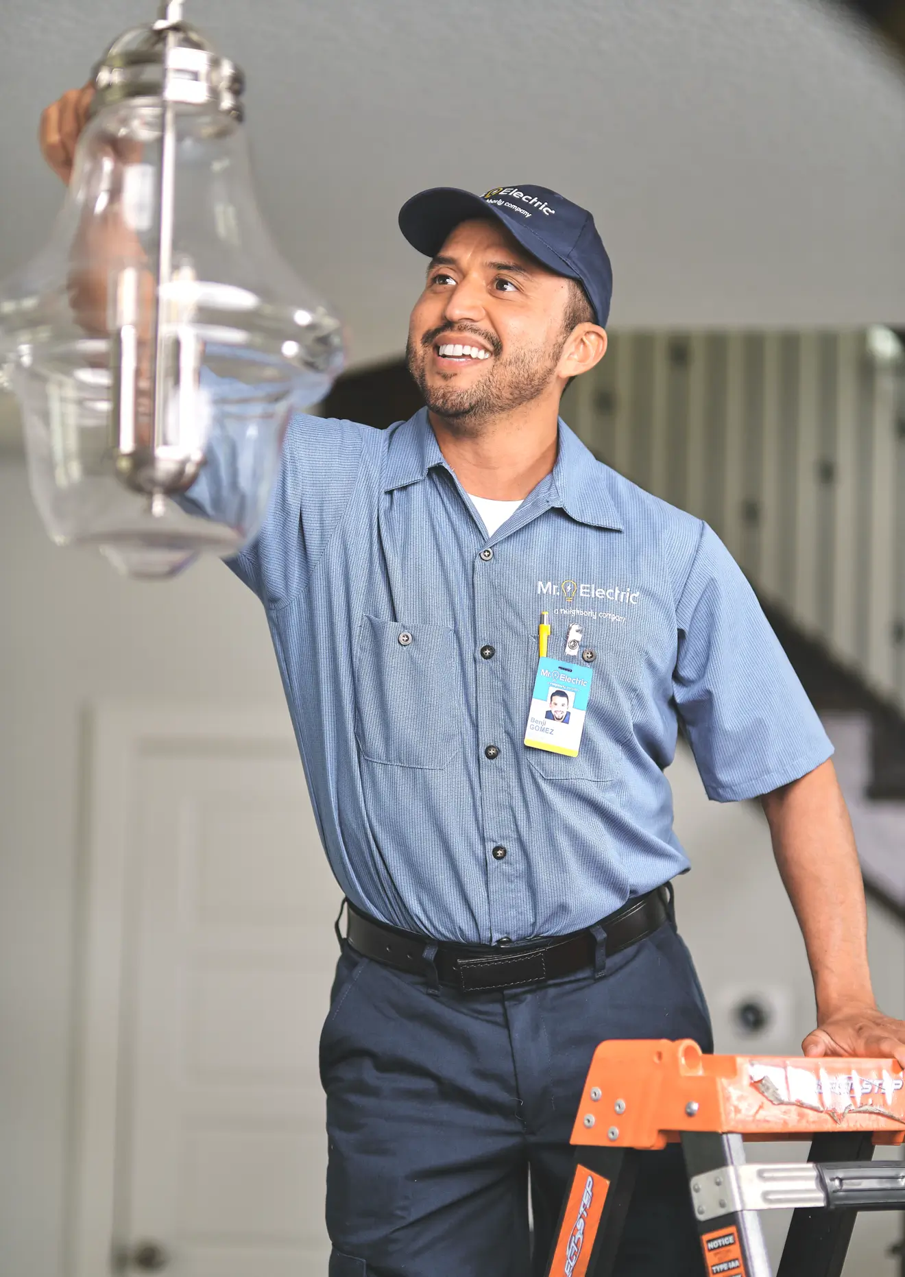 Electrician replacing hanging ceiling light fixture.