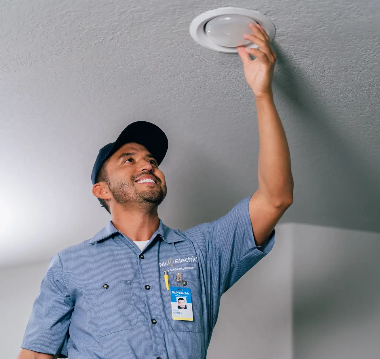 Electrician changing recessed ceiling light bulb.