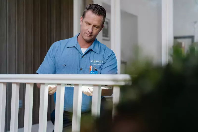 A Mr. Electric electrician installing lighting on a piece of deck railing