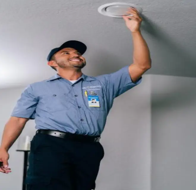 Mr. Electric electrician replacing a light bulb.