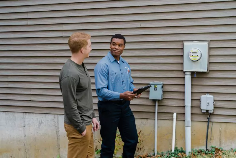 Mr. Electric electrician & customer behind a building discussing commercial generator options.