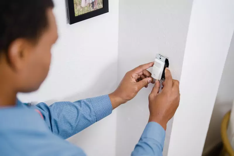 A Mr. Electric electrician installing a light sensor 