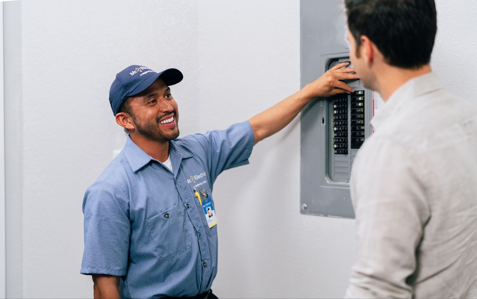 Mr. Electric technician showing panel to customer.