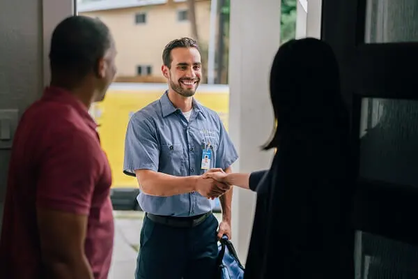 A couple in an open doorway and the woman shaking hands with a Mr. Electric electrician outside.