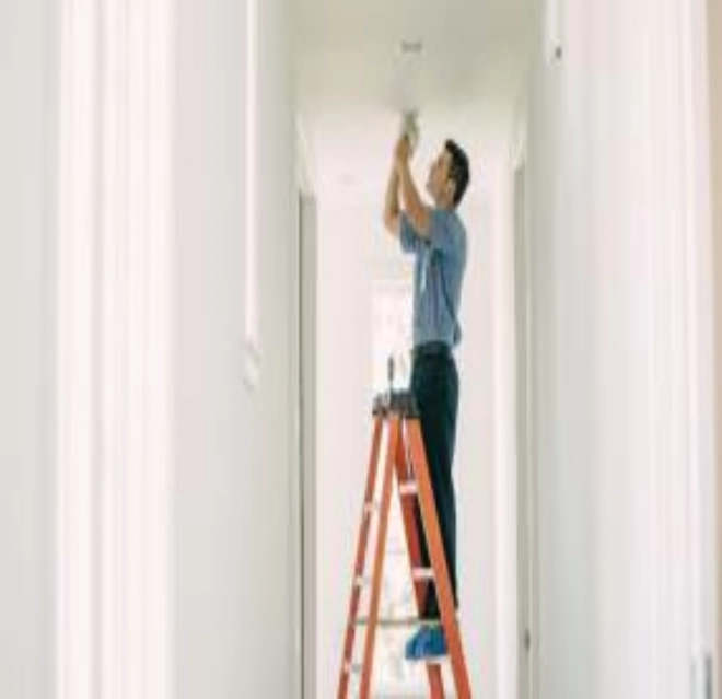 Mr. Electric electrician repairing a hallway light at a customer's home.