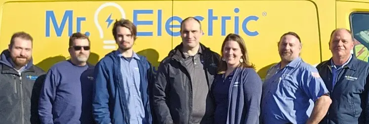 Row of smiling Mr. Electric of Salem associates standing outdoors in front of Mr. Electric truck.