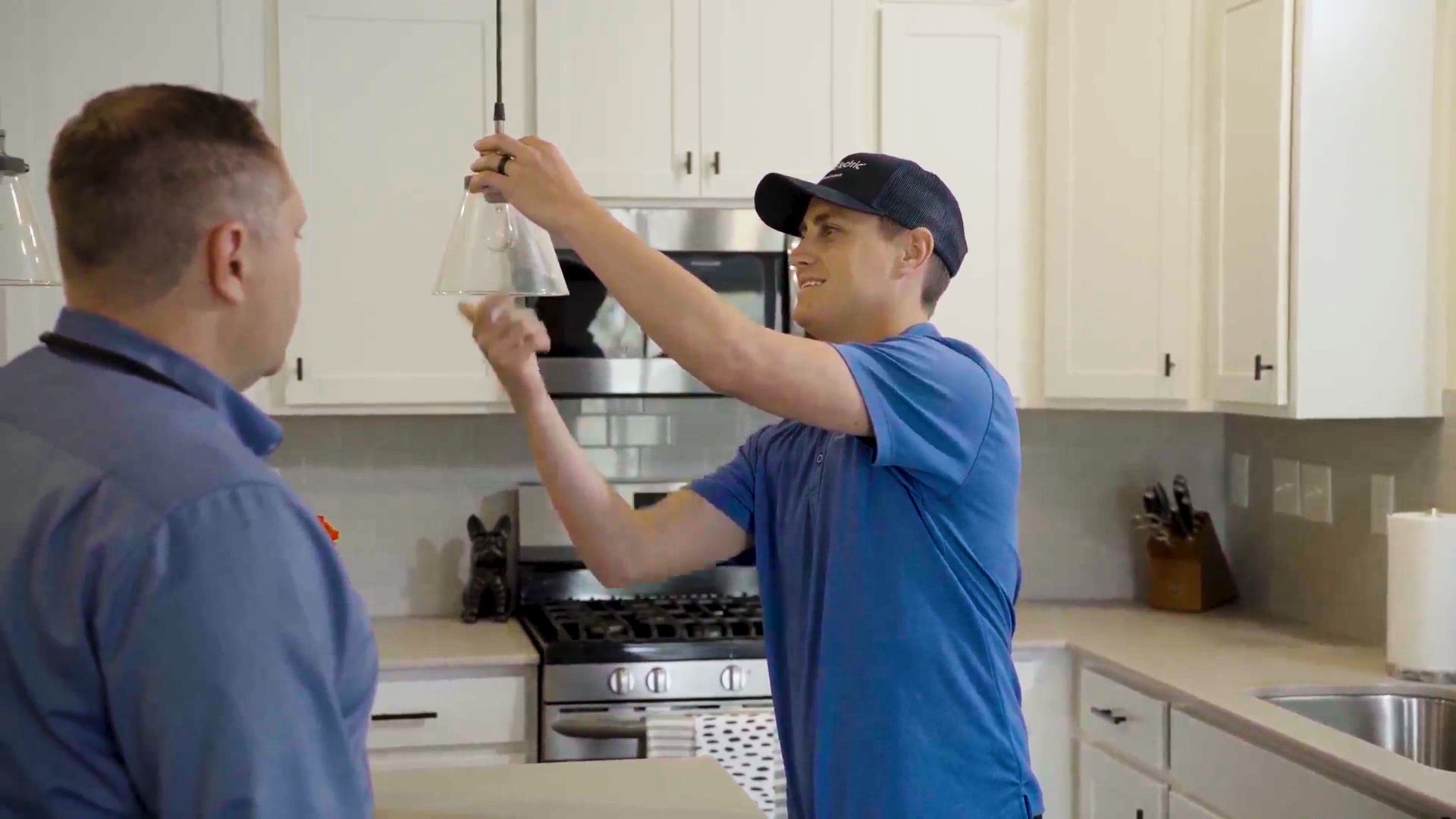 Professional electrician installing a smart thermostat in a home.