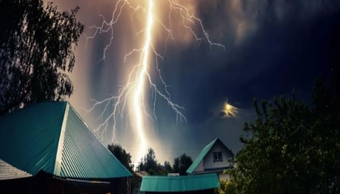 Thunderbolt over the house with dark stormy sky in the background and moon shining through the cloud.