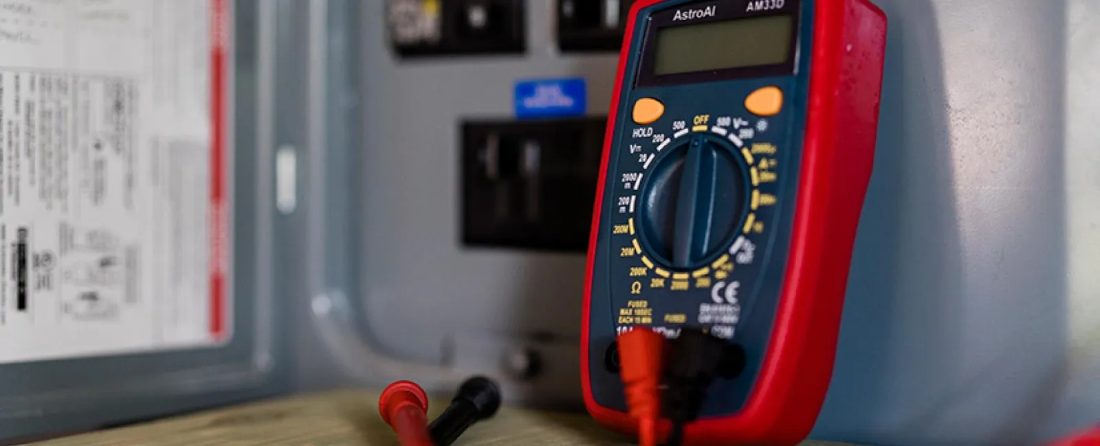 A multimeter on top of a wooden table.