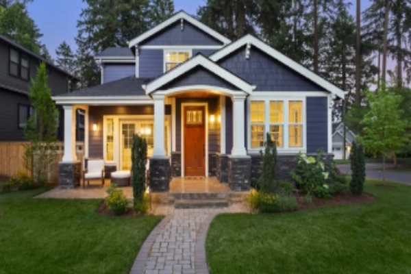 Exterior of beautiful suburban home at twilight with stone walkway and a nice green lawn and elegant exterior lighting