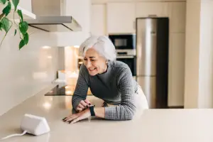 Senior woman in her kitchen speaking to her smart home device setup by Mr. Electric during a smart home installation service.