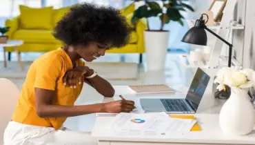 A side view of smiling young female freelancer working at home office.