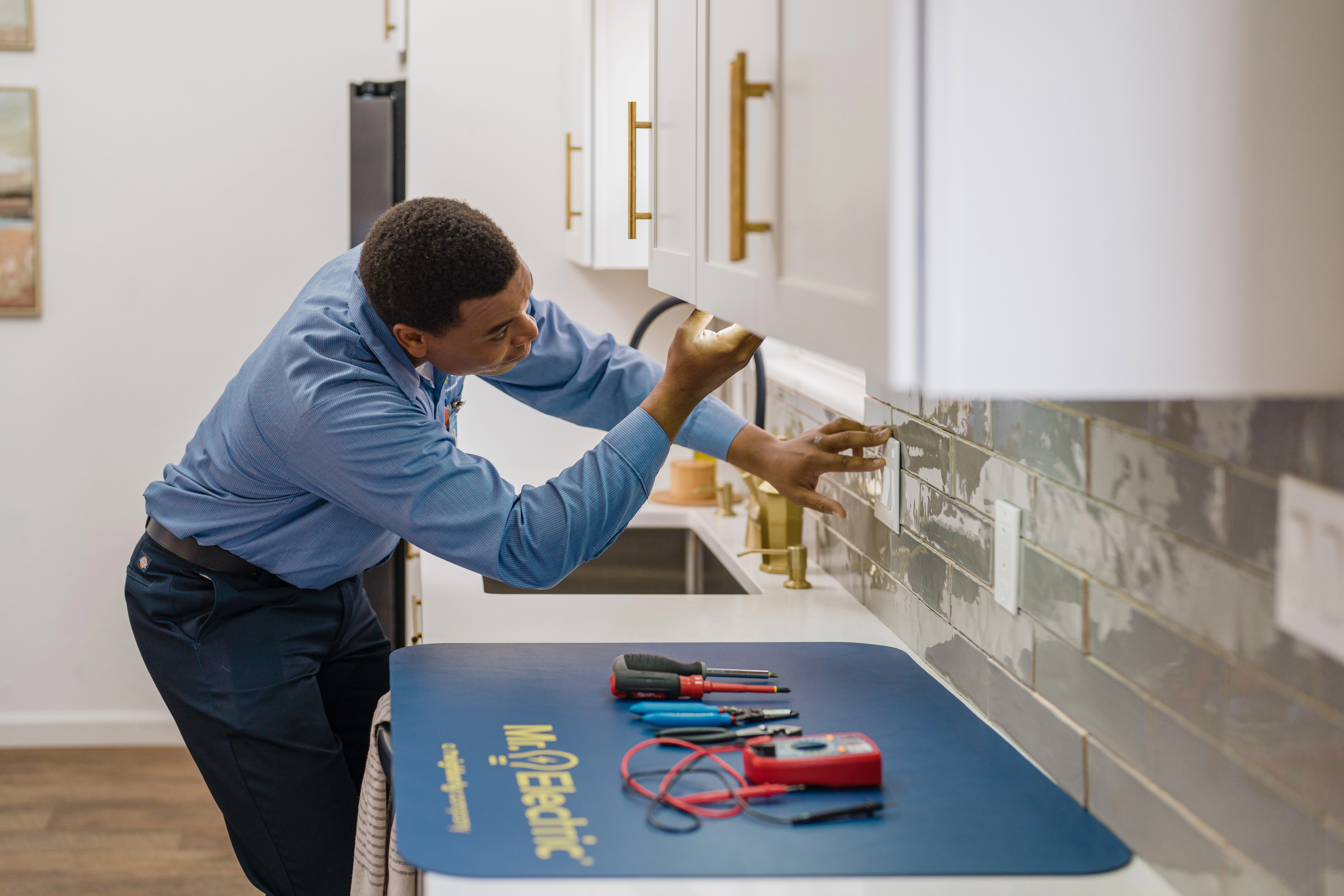 A Mr. Electric electrician checking the outlets in a client's kitchen.