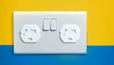 Outlet with outlet covers on a wall painted half yellow and half blue.