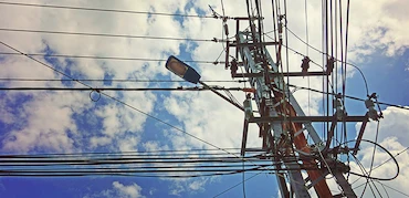 Looking up at utility pole with clouds in the background.