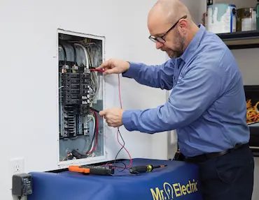 Professional Mr. Electric technician testing a residential electrical panel to ensure home safety during National Electrical Safety Month.